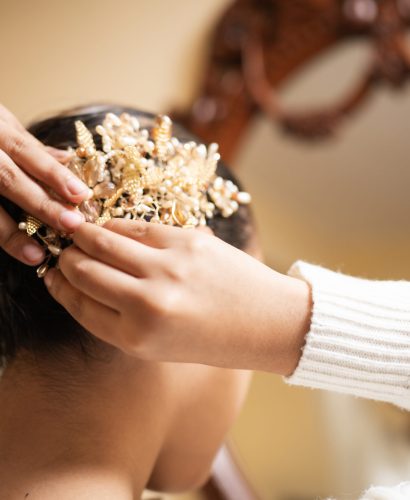 Woman is placing a beautiful hairpin with floral ornaments on the hair of another woman, getting her ready for a special occasion